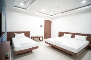 Royal Majestic Lodge في غاواهاتي: سريرين في غرفة بجدران بيضاء +10 صور