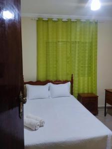 - une chambre avec un lit et un rideau vert dans l'établissement Casa OLiveira, à Cachoeira Paulista