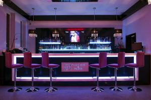 eine Bar mit roten Stühlen und einem Fernseher in einem Zimmer in der Unterkunft Hotel Vega in Lębork