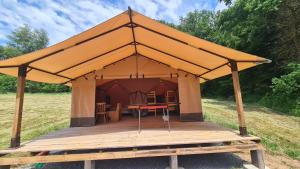 a tent with a wooden deck in a field at Tente lodge la perche in Le Lonzac