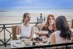 a group of women sitting around a table with food at No 42 by GuestHouse, Margate in Margate