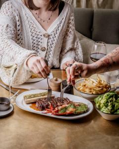 a woman sitting at a table with a plate of food at No 42 by GuestHouse, Margate in Margate