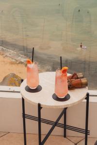 a table with two cocktails on top of a table next to a beach at No 42 by GuestHouse, Margate in Margate
