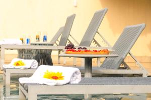 two chairs and a table with a tray of fruit at PÉ NA AREIA, DE FRENTE PARA A PRAIA - Casa Paraíso dos Corais 8 suítes, Praia Guarajuba in Guarajuba