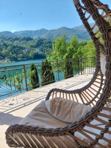a wicker chair sitting on a balcony overlooking a river at Villa AS sa bazenom na Jablaničkom jezeru in Konjic