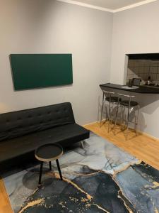 a living room with a black couch and a table at Przytulne Studio Góry Sowie in Bielawa