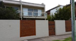 a house with a white and wooden fence in front of it at The Esplanade Holiday Home in Indented Head