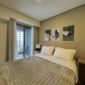 a bedroom with a large bed and a balcony at Studios Prime Pivô Match - Jardins in Sao Paulo