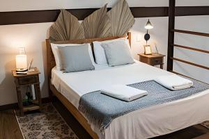 een slaapkamer met een groot bed met witte lakens en kussens bij Perequê Center in Ilhabela