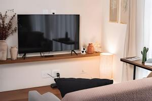 een woonkamer met een flatscreen-tv aan de muur bij Perequê Center in Ilhabela