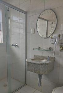a bathroom with a sink and a mirror and a shower at Hotel Colonial in Irati