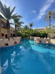 a large swimming pool with chairs and palm trees at Aldar Inn - نزل الدار in Nizwa +34 photos
