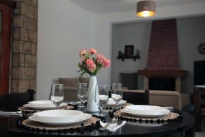 a table with plates and glasses and a vase with flowers at Villa Tzekos in Epanomi