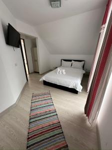 a bedroom with a white bed and a rug at Cabana Caterina in Topliţa