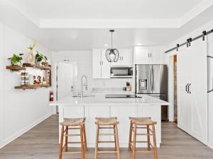 a kitchen with white cabinets and bar stools at Anastasia Island Villa Upper Level plus Rooftop in St. Augustine