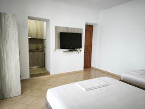 a white room with a bed and a tv at Vila Andoni in Qeparo