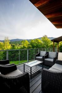 a deck with chairs and a coffee table on a balcony at 4BR - 2 Mstr Suites, Hot Tub, Prime Views, Privacy in Waitsfield