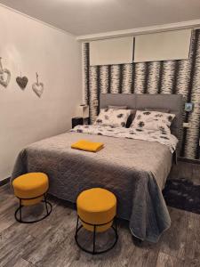 a bedroom with a bed with two orange chairs at Plitvice Green Gold Apartments in Korenica
