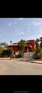 a red building with a fence on the side of a street at Las Colinas Beach in Manilva