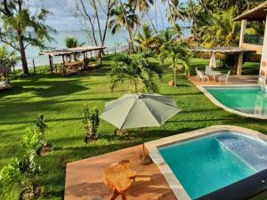 an umbrella and a chair next to a swimming pool at Bangalôs de Peroba in Maragogi