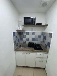 a small kitchen with a sink and a microwave at Praia Mansa Suite Hotel Flat in Fortaleza