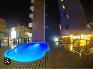 a large blue swimming pool on a deck at night at Praia Mansa Suite Hotel Flat in Fortaleza
