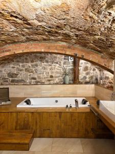 a bath tub in a bathroom with a stone wall at Suíte Sant Sebastià con jacuzzi, sauna y jardín in Moià
