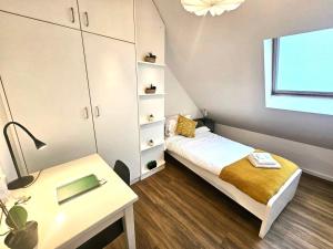 Un pequeño dormitorio con una cama y una mesa. en Luxembourg Living Stylish 2BR and Free parking, en Luxemburgo