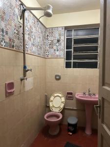 een badkamer met een roze toilet en een wastafel bij Casa benção de mãe in Aparecida +7 foto's