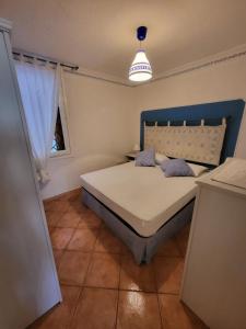 a bedroom with a bed with a blue headboard and a window at Bilocale presso Costa Smeralda in Cugnana Verde +7 photos