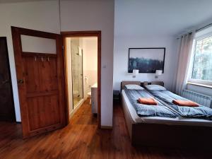 a bedroom with a large bed and a bathroom at Dom wakacyjny i Domki letniskowe nad Tanwią Roztocze in Narol