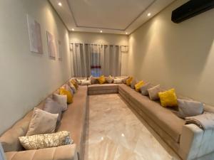 a living room with a long couch with yellow pillows at Appartement de haut standing,4 piscines in Bouznika
