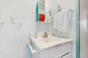 a white bathroom with a sink and a mirror at Uncle Rolfs Cozy Cottage in Dennis Port +8 photos