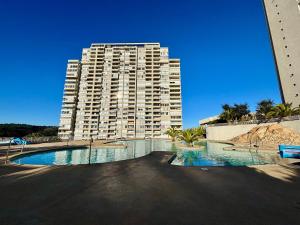 维纳德马Comodo Depto con hermosa vista的一座大型公寓楼,前面设有一个游泳池 更多15张照片