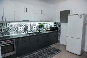 a kitchen with black cabinets and a white refrigerator at Villa Tzekos in Epanomi +16 photos