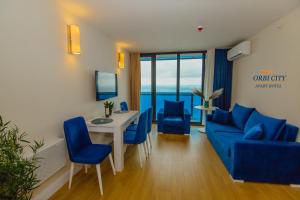 Una sala de estar con un sofá, una mesa y sillas. en APART-HOTEL ORBI CITY, en Batumi