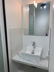 łazienka z białą umywalką i lustrem w obiekcie studio Cosy proche hyper centre w mieście Quimper