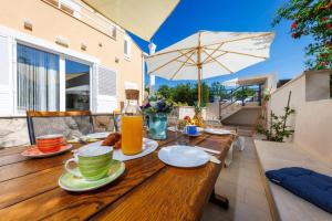 un tavolo in legno con piatti di cibo e un ombrello di Villa "Amber" relaxation in nature with a Pool a Mlini
