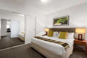 ein Hotelzimmer mit einem großen Bett und einem Spiegel in der Unterkunft Quest Jolimont in Melbourne