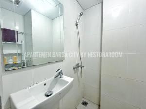 une salle de bain avec un lavabo et un miroir dans l'établissement Apartemen Barsa City ByNestoraroom, à Seturan