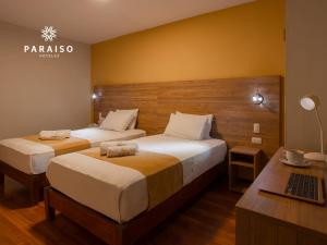 una habitación de hotel con 2 camas y un ordenador portátil en un escritorio en Hoteles Paraiso CHICLAYO, en Chiclayo