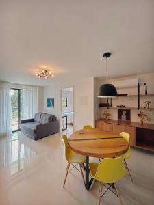 a living room with a wooden table and yellow chairs at Apartamento Artsy in Itaipava