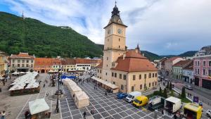 a building with a clock tower in a city at Town Square Loft Apartment in Braşov