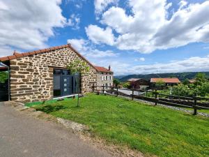 a stone house with a green yard next to a fence at Appartement Duplex les Cerisiers - Bilhac in Polignac