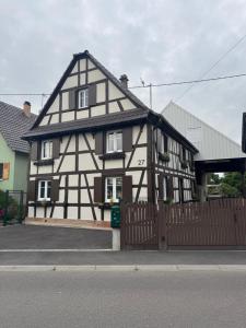 a black and white building with a wooden fence at Maison Alsacienne Centre Alsace in Hilsenheim