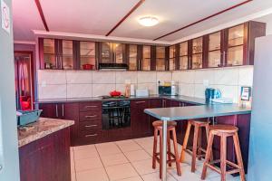a kitchen with wooden cabinets and a counter with stools at Mossie Inn Accommodation in Swakopmund