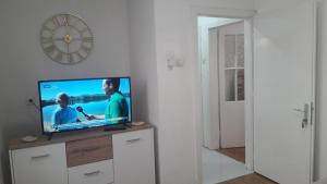 a television on a dresser with a clock on the wall at Bascarsija in Ulcinj +9 photos