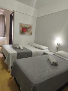 a room with three beds and a painting on the wall at Hotel Colonial in Irati