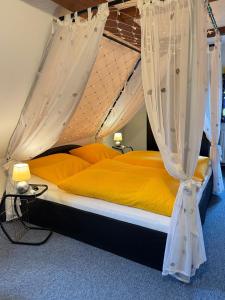 a bedroom with a bed with yellow sheets and curtains at Landhaus Sorgenfrei obere Etage in Hohnstein