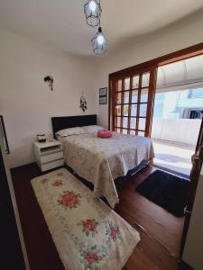 a bedroom with a bed and a table and a window at Quarto familiar na cidade do Cristo in Encantado
